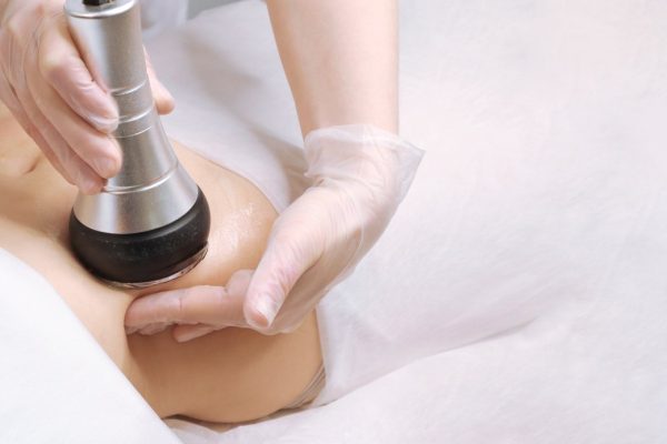 The cavitation procedure closeup. Beautician apparatus for cavitation on the woman's stomach. The concept of skin care face and body