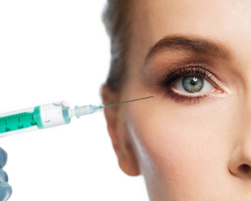people, cosmetology, plastic surgery and beauty concept - beautiful young woman face and beautician hand in glove with syringe making injection over white background
